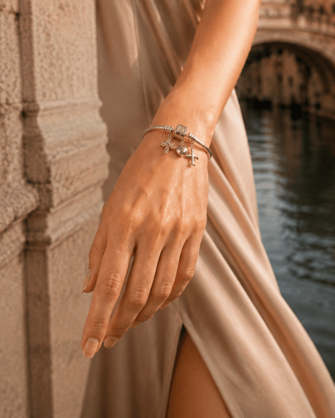 Sterling silver charm bracelet styled on a wrist in Venice